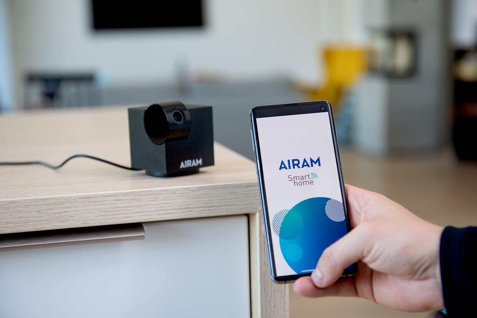 Airam SmartHome IP20 kamera olohuoneen pöydällä ja sovelluskuva